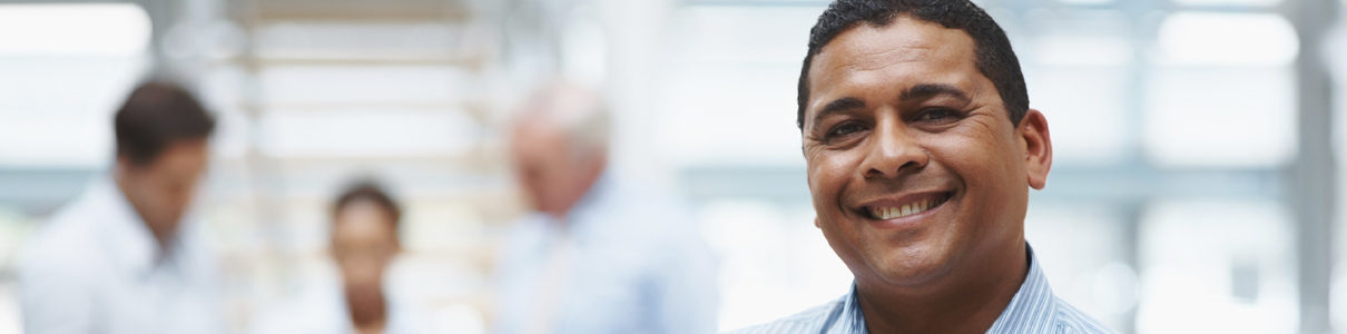 careers-header-1 A man in an office setting looking at the camera and smiling