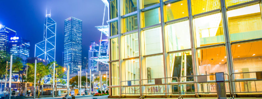 Nighttime exterior of a ground-level retail space with skyscrapers visible behind the corner of the building