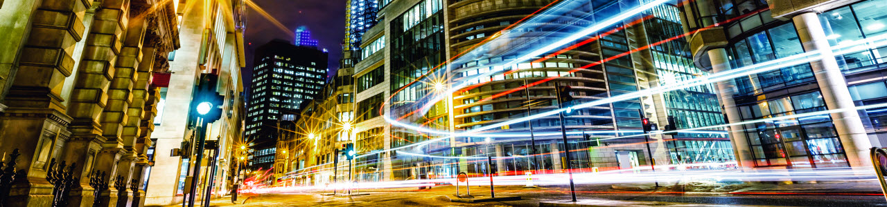 Concept image showing streaks of light moving through a city business block at night