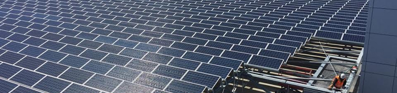 A worker inspects solar panels on the roof of a parking garage at Minneapolis-St. Paul International Airport