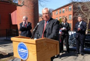 Boston Mayor Thomas M. Menino speaks at a podium at a press event at the Bromley-Heath Housing Project