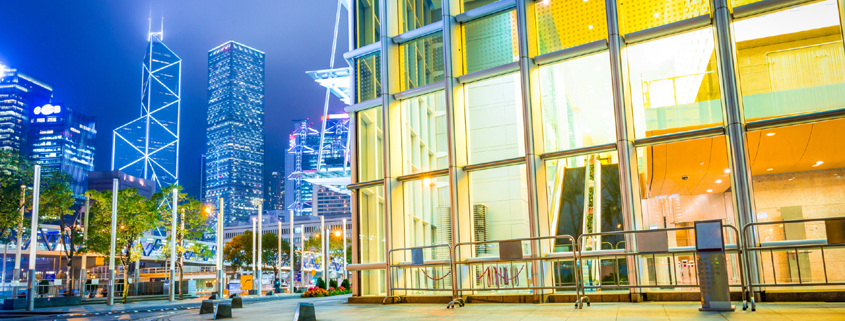 Nighttime exterior of a commercial buildiing with the Sydney skyline behind it