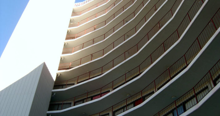 Close-up daytime exterior of railed porches on the front of a high rise residential building owned by the San Francisco Housing Authority