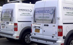 Daytime view of Ameresco-branded minivans parked outside a facility