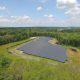 Daytime aerial view of a Blue Cross Blue Shield of Massachusetts solar farm in a wooded area