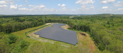blue-cross-blue-shield-large-case-study-thumb Daytime aerial view of a Blue Cross Blue Shield of Massachusetts solar farm in a wooded area