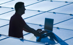 ameresco-solar-energy-soliutions-service-sheet Daytime view of a worker with a laptop in silhouette amid a field of solar panels