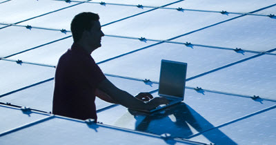 solar-energy-service-sheet-featured Worker with a laptop silhouetted against a field of solar panels