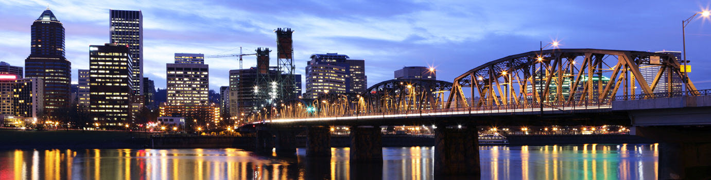 Evening view of Portland, Oregon with a river and bridge in the foreground