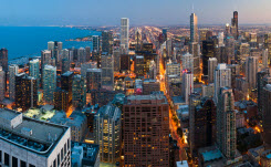 Aerial view of the downtown Chicago skyline at dusk with Lake Michigan to the left.