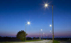 View of LED streetlights along an empty suburban road at sunset.