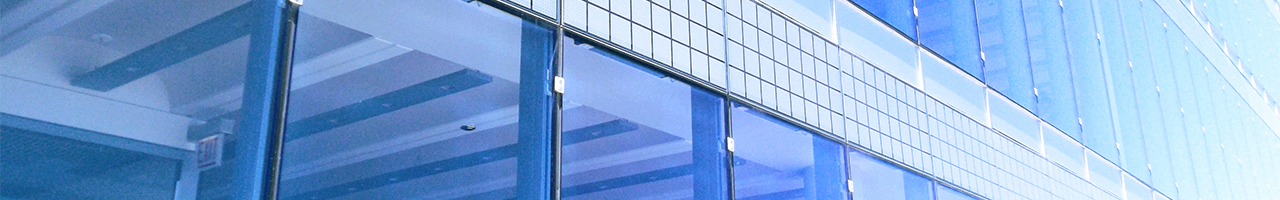 Close up view of a modern office building showing a bit of the concrete ceiling and a section of exterior tiles between two rows of glass