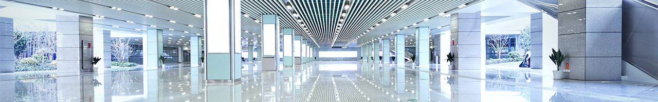 Interior view of a brightly lit and modern building entryway in shades of white, light grey and seafoam green