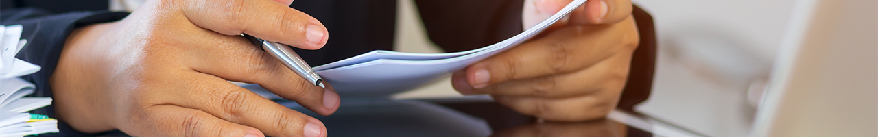 Interior closeup of an executive reviewing data on a printout and a tablet computer