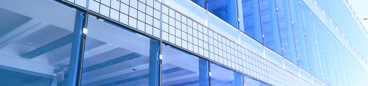 Daytime closeup of the side of a modern skyscraper showing a tiled wall separating two areas of glass