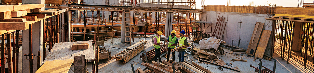 View of three workers in the middle of a building under construction, standing on an upper floor