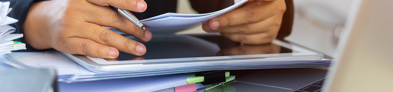 Close up interior view of a person reviewing data on a printout and a tablet computer