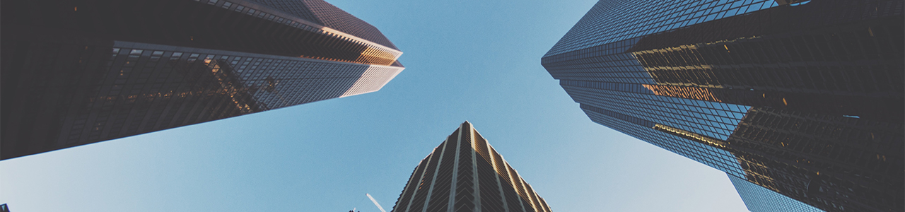 Daytime view from street level looking straight up at three skyscrapers