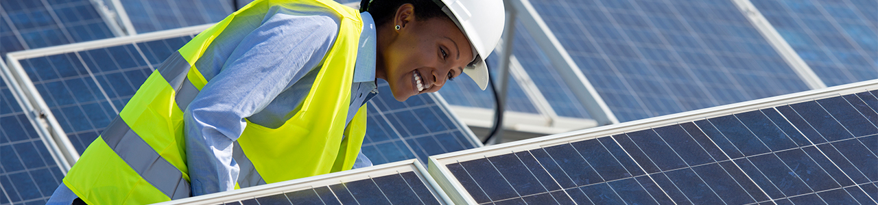 Daytime close up view of a worker examining solar panels in a solar array
