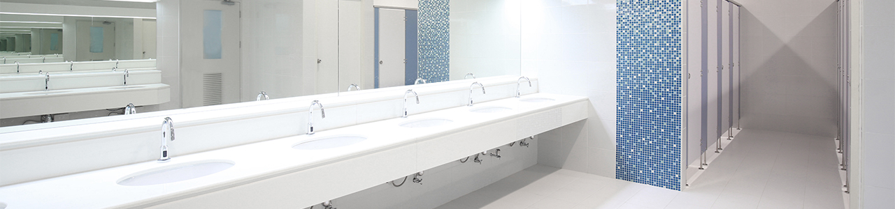 Interior view of a restroom in a large building showing a row of sinks with touchless, high-efficiency controls