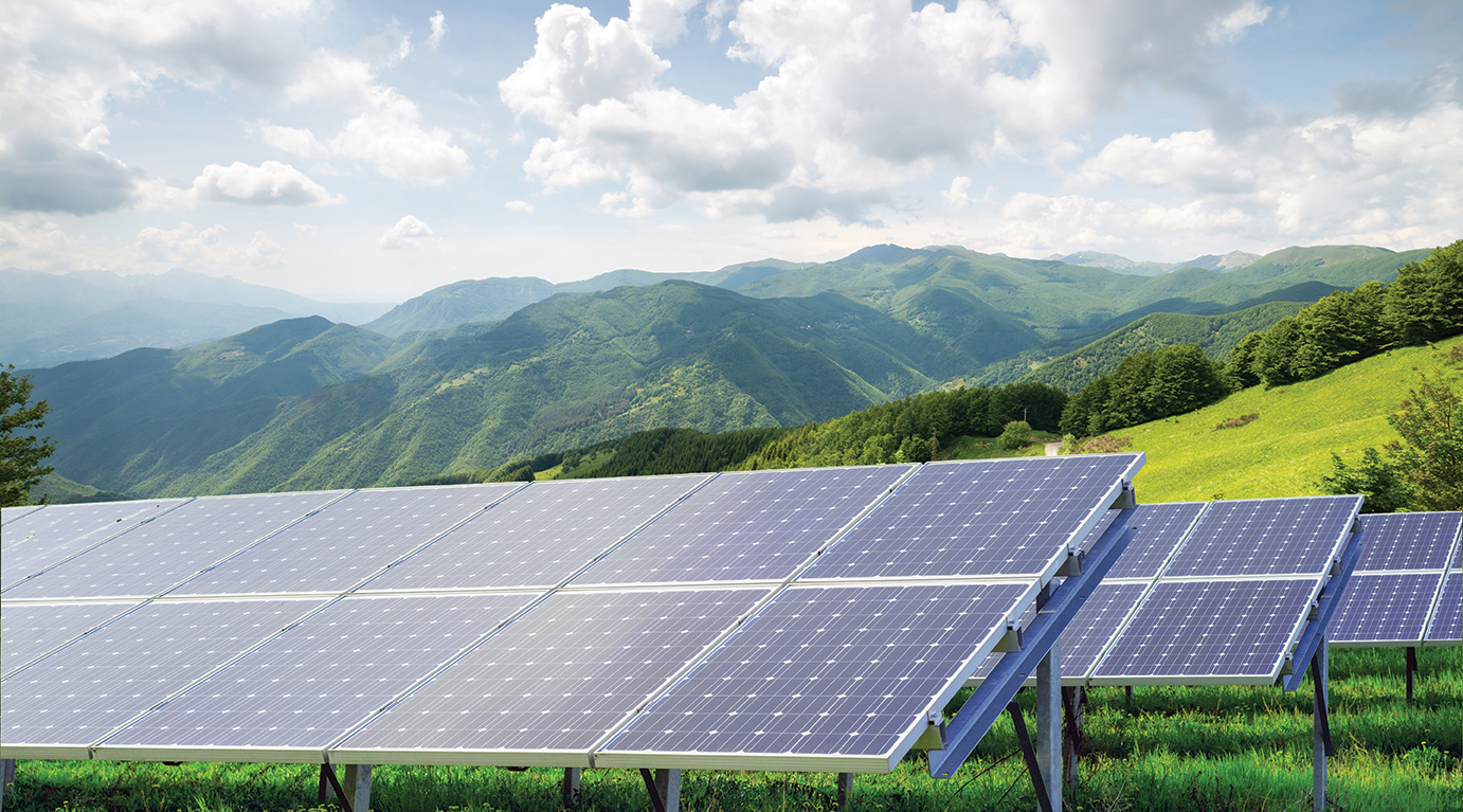 Daytime view of solar panels with mountains in background and blue sky