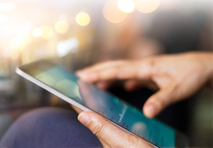 Close up of hands and a tablet computer with a chart on its screen