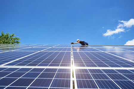 Daytime view of a worker inspecting solar panels in an array