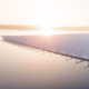 The sun sets behind a lake with a floating solar-panel farm