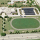Aerial view of John Paiul II Catholic Secondary School in Ontario, Canada with rendered solar car ports and battery storage systems