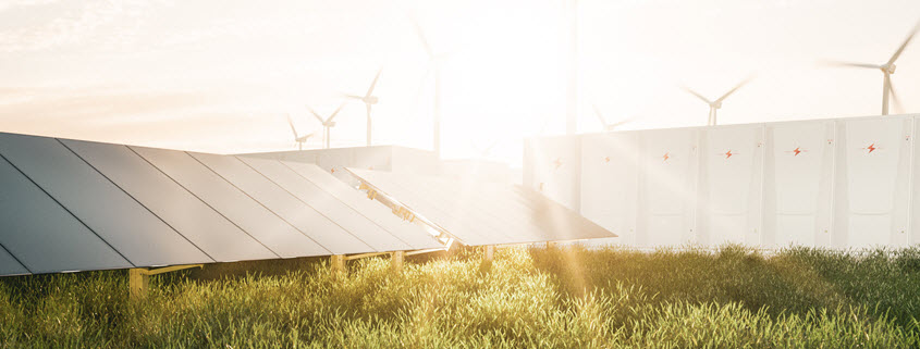Concept image for renewable energy shows wind turbines, solar panels and battery enclosures with a sunrise behind them