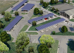 Daytime aerial view of a main building at Joint Base San Antonio showing renderings of rooftop and carport solar panels