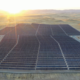 Aerial view of a large solar farm in San Joaquin County with the sun setting behind mountains in the distance