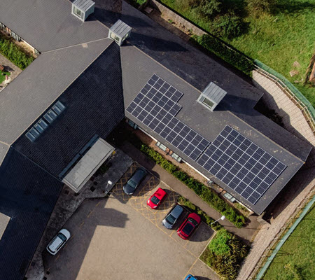 Daytime aerial view of a rooftop solar installation on a building managed by Merthyr Tdyfil Town Council