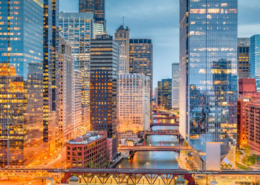 Downtown Chicago at sunset with buildings on either side of the river illuminated