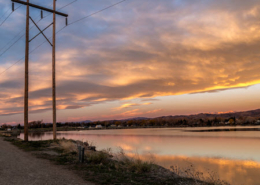 Sunset view of a high-tension utility tower next to a river in Colorado