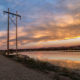 Sunset view of a high-tension utility tower next to a river in Colorado