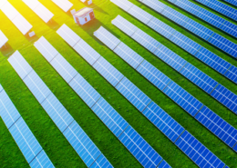 Daytime aerial view of a solar farm lit by bright sunshine