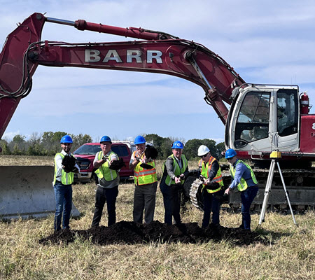 Daytime view of a groundbreaking in front of a backhoe for a battery energy storage system in Napanee