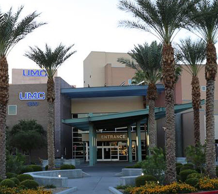 Daytime exterior of the main entrance of University Medical Center flanked by palm trees