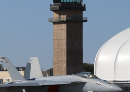 Daytime view of a jet in front of the control tower at NHS Lemoore