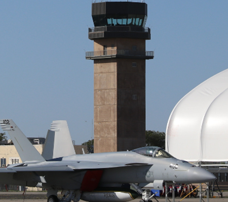 Daytime view of a jet in front of the control tower at NHS Lemoore