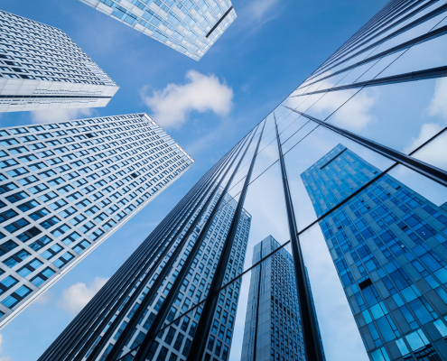 Daytime view looking up at skyscrapers under a blue sky