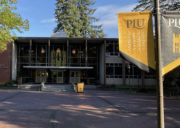 Daytime view of the administration building at Pacific Lutheran University with school banners in the foreground