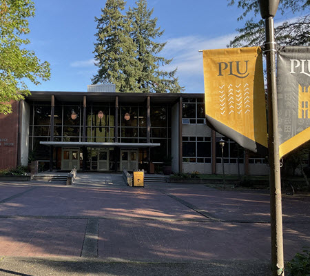 Daytime view of the administration building at Pacific Lutheran University with school banners in the foreground