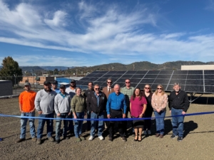RUSA Ribbon Cutting Roseburg Urban Sanitary Authority OR people at ribbon cutting in front of solar panel