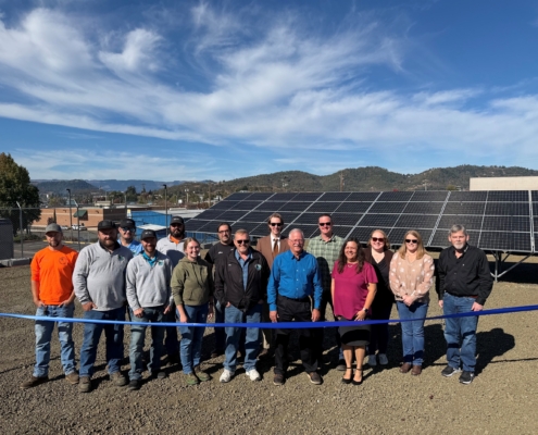 Roseburg Urban Sanitary Authority OR people at ribbon cutting in front of solar panel